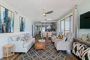 A spacious living room with a sofa, armchairs, a coffee table, and a dining area with chairs and a table.