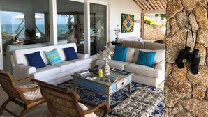Ein geräumiger Wohnbereich mit einem weißen Sofa, blauen Kissen, einem Holztisch und einem gemusterten Teppich.