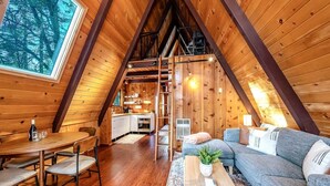 A cozy cabin interior with a dining area, sofa, and kitchen.