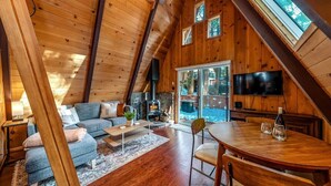 A cozy, wooden interior with a loft-style ceiling, a stone fireplace, and a dining area.