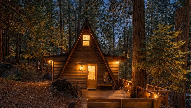 A cabin with a wooden exterior, a porch, and a staircase leading to the entrance.