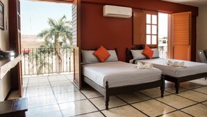 Una habitación con dos camas, aire acondicionado y un balcón con vistas a palmeras.