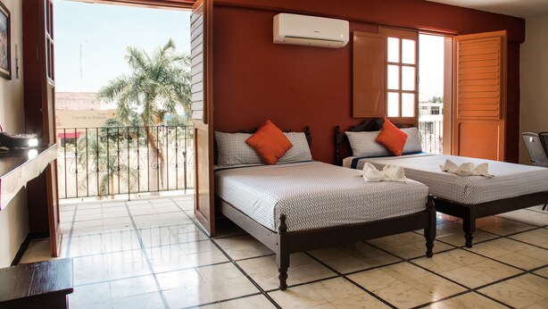 Una habitación con dos camas, aire acondicionado y un balcón con vistas a palmeras.
