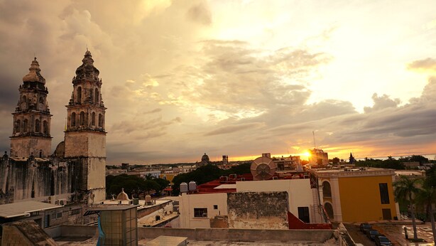 Un paisaje urbano histórico con torres destacadas y un atardecer.