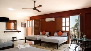 Habitación de hotel con dos camas, ventilador de techo, equipo de aire acondicionado, una mesita y una silla.
