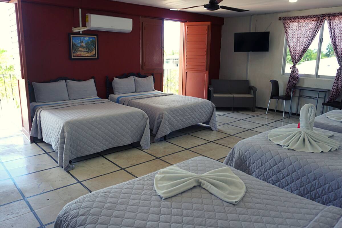 A hotel room with two beds, a desk, a chair, a TV, and a window with curtains.