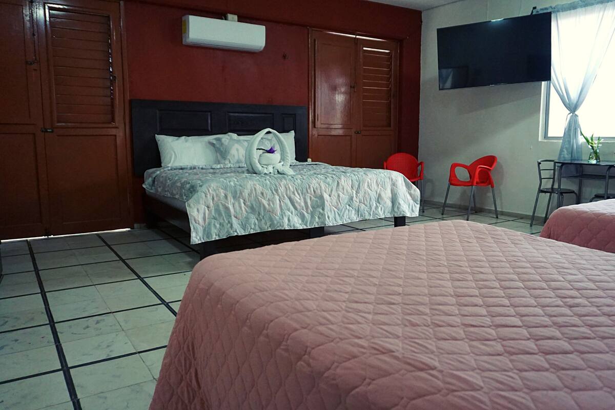 A hotel room with a bed, a TV, a desk, and chairs.