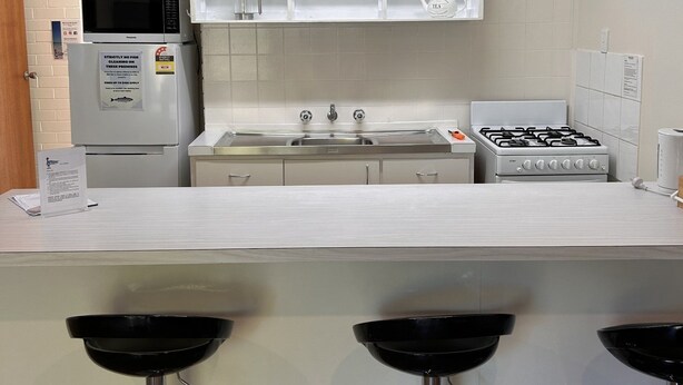 Una cocina moderna con encimera blanca, electrodomésticos de acero inoxidable y microondas integrado.