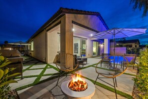 Relax by the fire pit in a luxurious outdoor space with comfortable seating and a nearby pool.