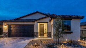 Stucco and stone detailing surround this charming home, featuring a two-car garage and a beautifully landscaped garden.