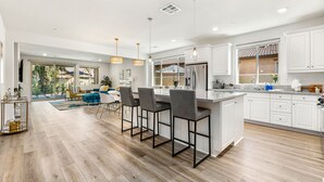 Cozinha moderna com ilha central, banquetas e iluminação pendente.