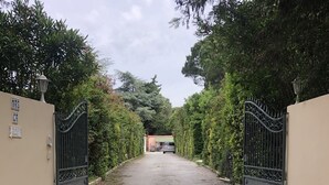 A gated driveway leading to a building with a parked van. - VILLA 230 m² - 16 Pers - 8chambres -4000m² de parc /piscine 10 x 5m a 5 mn plage (Argelès-sur-Mer)