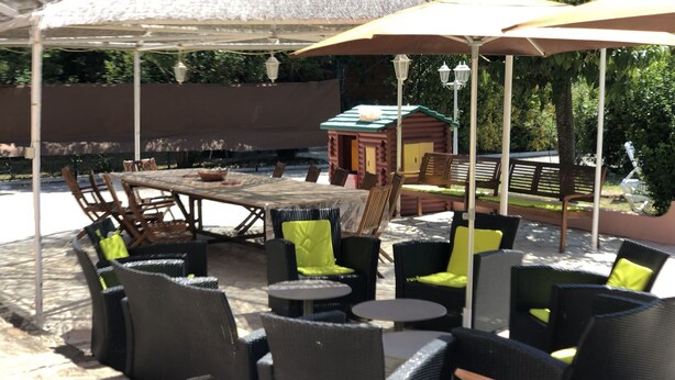 An outdoor patio with wicker furniture, a wooden table, and a small cabin structure in the background. - VILLA 230 m² - 16 Pers - 8chambres -4000m² de parc /piscine 10 x 5m a 5 mn plage (Argelès-sur-Mer)