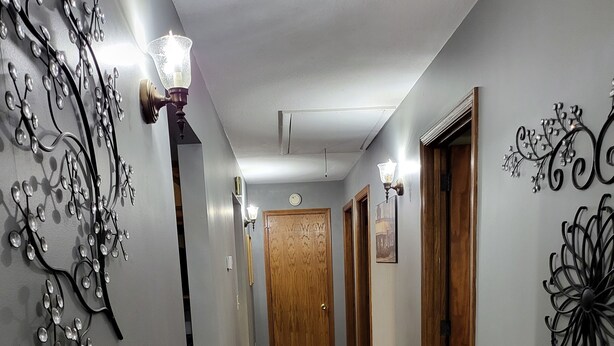 Un pasillo con suelo de madera, decoración en las paredes y una puerta de madera al final.