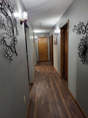 Un couloir doté d’un plancher en bois, agrémenté d’œuvres d’art murales décoratives, et une porte en bois au bout.