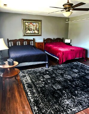 A bedroom with two beds, a wooden floor, a ceiling fan, a nightstand, a lamp, and a framed picture on the wall. - 1500 Sq.ft. of Quaint Comfort in the heart of Olney close to downtown! (Olney)