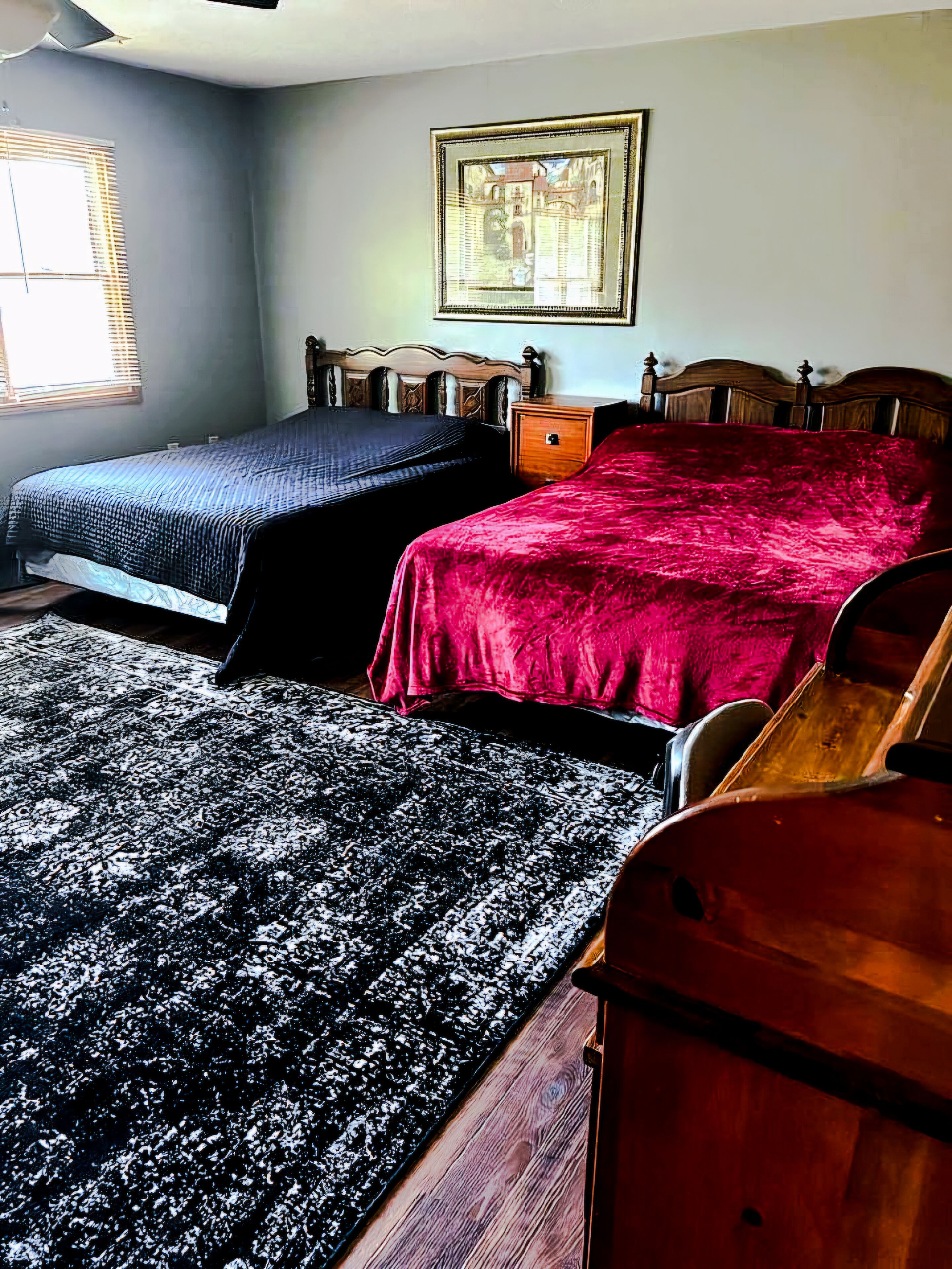 Une chambre avec deux lits, une table de chevet en bois, une commode et un tableau encadré au mur.