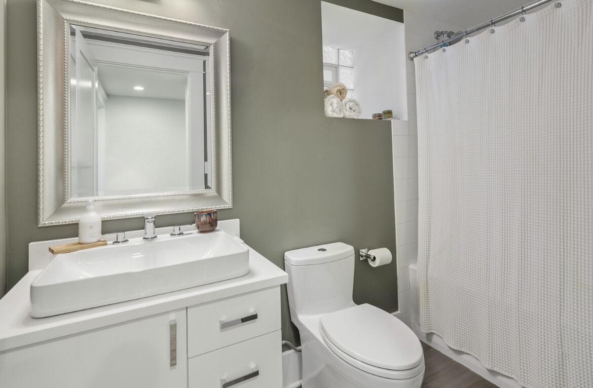 Une salle de bain avec un lavabo blanc, un miroir et des toilettes.