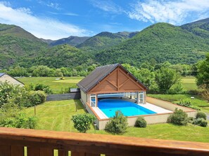 Una casa con piscina, rodeada de colinas y montañas verdes y exuberantes.