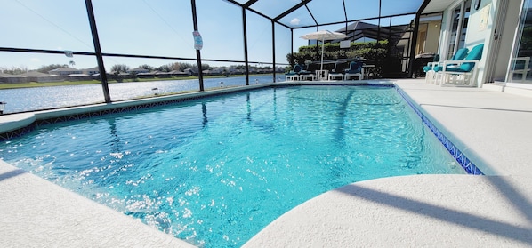 Piscina com vista para a água e área coberta com espreguiçadeiras.