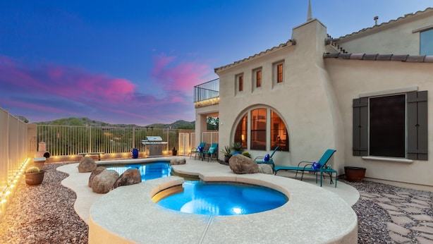 Un espace piscine comprenant un jacuzzi, des chaises longues et une terrasse offrant une vue sur les montagnes.
