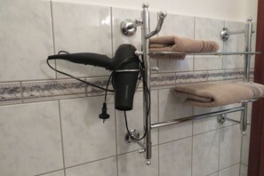 Ein Badezimmer mit Handtuchhalter, zwei Handtüchern, einem Föhn und einem chromfarbenen Wasserhahn.