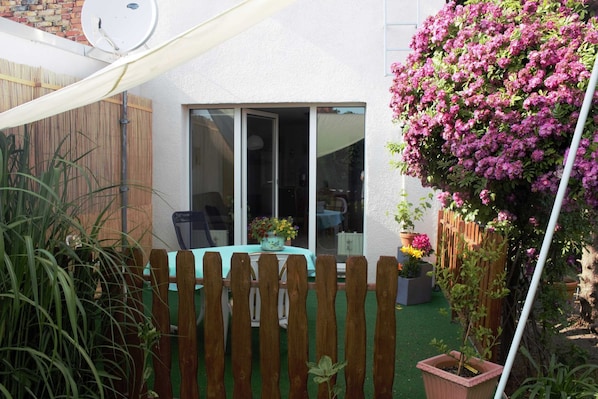 A patio with a wooden fence, a table with chairs, and a potted plant.