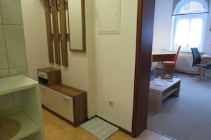 A hallway with a wooden bench, a desk with a chair, and a window with blinds.