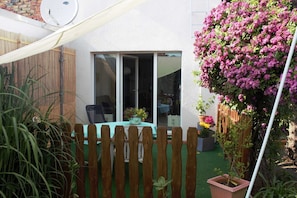 Eine Terrasse mit Holzlattenzaun, einem Tisch mit Stühlen und einem Blumentopf.