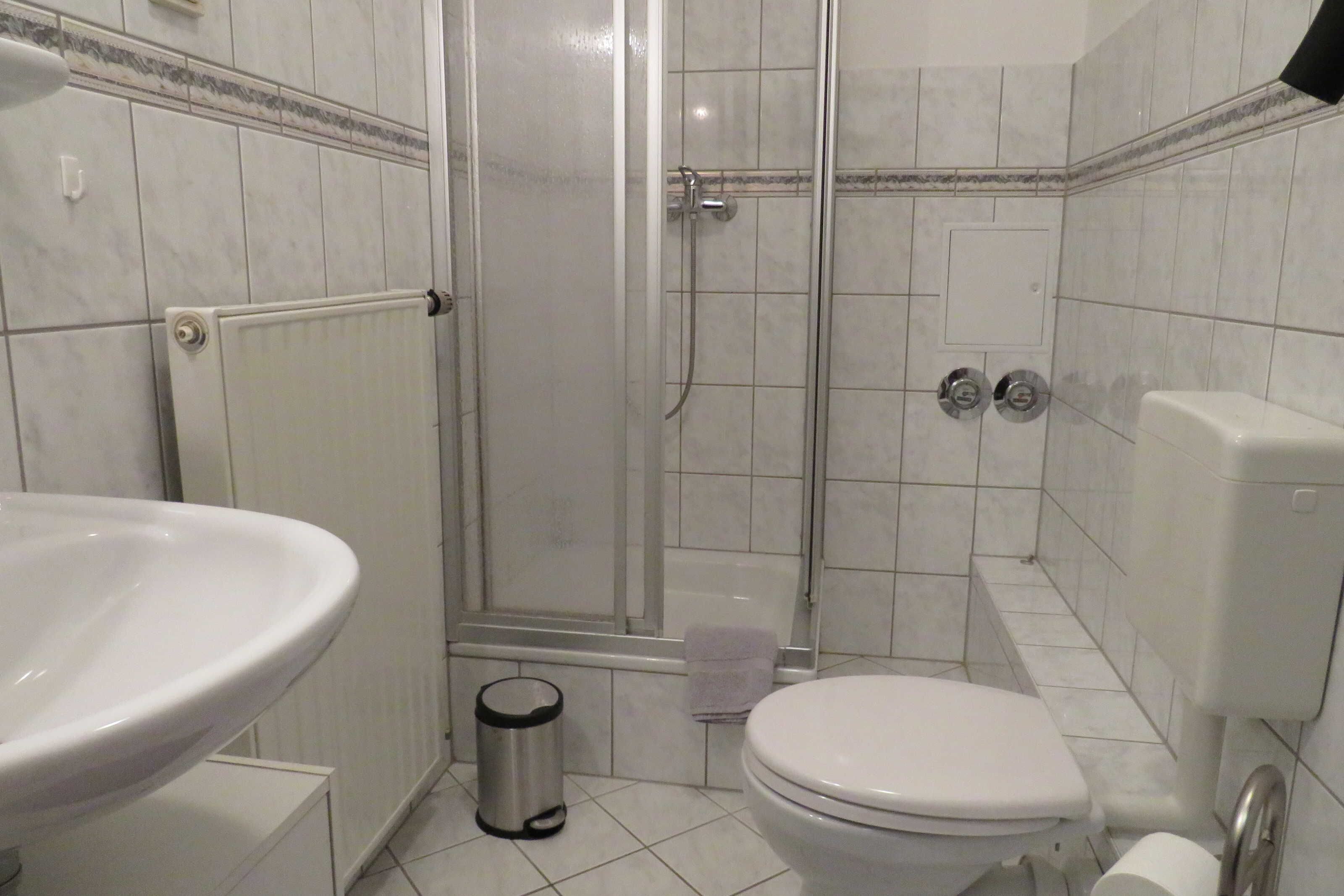 Ein Badezimmer mit Dusche, Toilette, Waschbecken und Mülleimer.