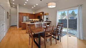 A spacious kitchen with wooden cabinets, a central island, and a dining area with a large table and chairs. - Dwell 30 Day Minimum- Modern & Peaceful, Walk to Old Mill, New and Lovely, AC (Bend)