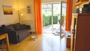 A living room with a sofa, a glass coffee table, a lamp, and a view of the outdoors through a glass door. - Vacation apartment 25 Nachtigallenweg (Graal-Müritz)