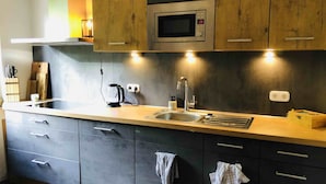 Una cucina moderna con forno a microonde integrato, bollitore e lavandino.