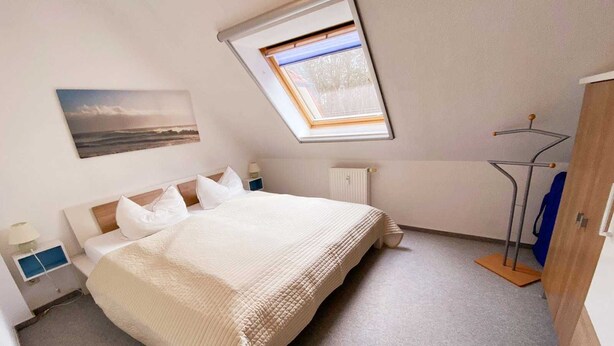 A bedroom with a bed, a radiator, a window, and a wardrobe. - Vacation apartment Haus Küste 9 (Graal-Müritz)
