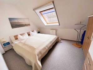 A bedroom with a bed, a radiator, a window, and a wardrobe. - Vacation apartment Haus Küste 9 (Graal-Müritz)