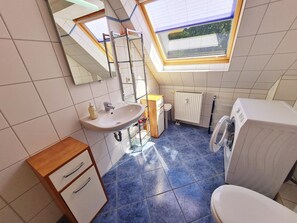 Un baño pequeño y moderno con tragaluz, un lavabo, un inodoro y una lavadora.