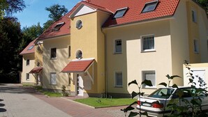 A two-story residential building with a red-tiled roof, multiple windows, and a paved driveway. - Vacation apartment Haus Küste 9 (Graal-Müritz)