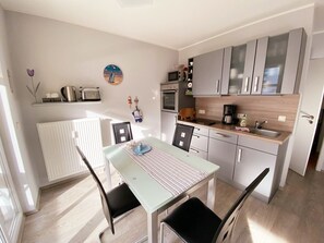 A compact kitchen with a dining table, chairs, and a microwave. - Vacation apartment Seeadler 1 (Graal-Müritz)