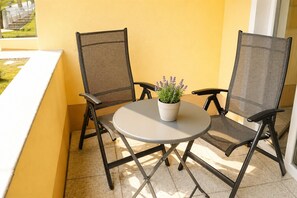 A balcony with two mesh chairs, a round table, and a potted plant. - Vacation apartment Seeadler 1 (Graal-Müritz)