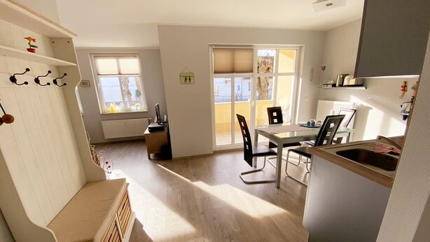 A modern kitchen with a dining area, wooden flooring, and a view through the windows. - Vacation apartment Seeadler 1 (Graal-Müritz)