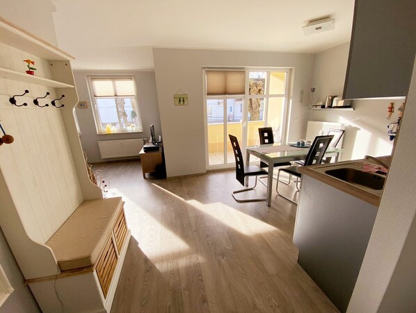 A modern kitchen with a dining area, wooden flooring, and a view through the windows.
