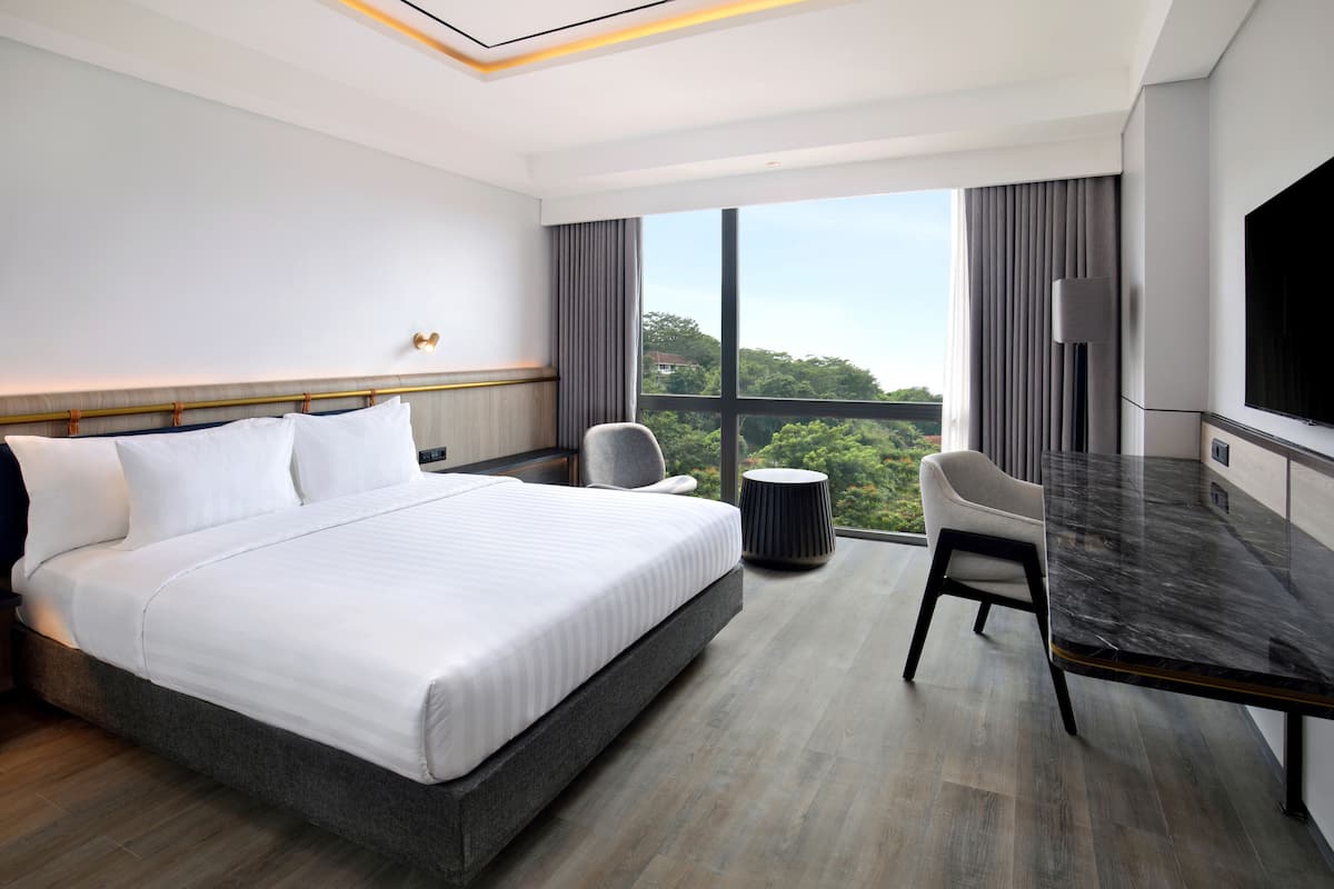A modern hotel room with a large bed, a desk, and a TV.