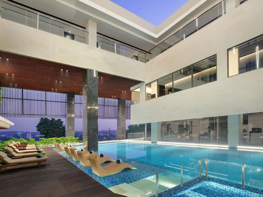 Area piscina interna moderna con sedie a sdraio e vista sulla città.