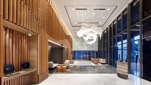 A modern lobby with a wooden reception desk, seating area, and large windows. - Hotel Aruss Semarang (Semarang)