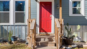 A wooden front porch with a red door, a potted plant, and a wooden fence. - Cute Cottage close in Downtown Waco close to Magnolia, Baylor Uni., Cameron Park (Waco)