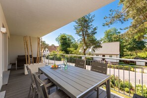 En balkon med et bord, stole og en potteplante.