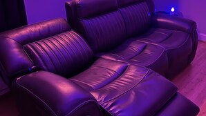 Una habitación con un sofá reclinable y un enchufe en la pared.