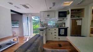 A compact kitchen with white cabinets, a microwave, and a small window.