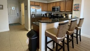 A modern kitchen with wooden cabinets, stainless steel appliances, and a bar area with wicker chairs. - 2BR/2BA-Sleeps 6
Seascape Condo at Miramar Beach (Destin)