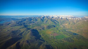 Vista aérea de uma paisagem montanhosa com vales, campos e edifícios dispersos.